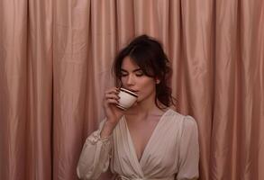 ai generado mujer Bebiendo té en frente de marrón cortina foto