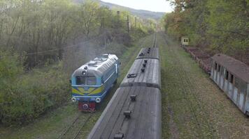 Aerial view of the train rides on the railroad. Drone flight over the locomotive and carriages of the narrow gauge railway. video