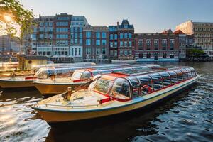 Tourist boats moored in Amsterdam canal pier on sunset photo