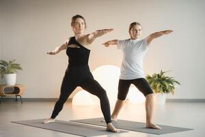 Mom and teenage daughter do gymnastics together in the fitness room. A woman and a girl train in the gym photo