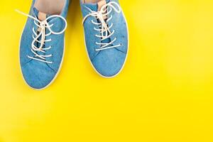 Blue shoes stand on an isolated yellow background photo