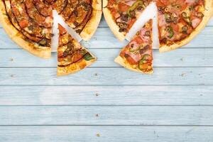 Two different delicious big pizzas on a blue wooden background photo