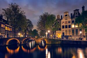 Ámsterdam canal, puente y medieval casas en el noche foto