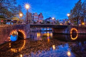 Amsterdam canal, puente y medieval casas en el noche foto