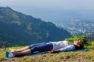 Woman relaxes in yoga asana Savasana outdoors photo