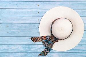 Top view of a straw white hat lying on a blue wooden background.The concept of summer holidays photo