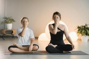 Mom and teenage daughter do gymnastics together in the fitness room. A woman and a girl train in the gym photo