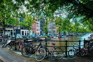 Amsterdam canal con barcos y bicicletas en un puente foto