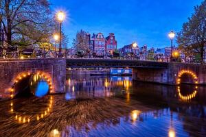 Amsterdam canal, puente y medieval casas en el noche foto