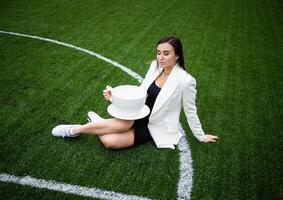 A business woman with a large cup, sitting on a green lawn in the park. photo