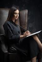 a young brunette female artist stands behind an easel. photo