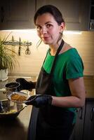 mujer Cocinando sabroso Derretido chocolate en mesa en cocina. foto