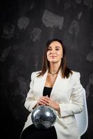 Portrait of a woman holding a silver disco ball. Taken in a photo studio.