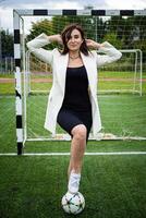 retrato de un hermosa mujer fútbol americano jugador en un estricto oficina traje. foto