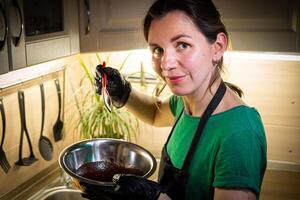 Woman cooking tasty melted chocolate on table in kitchen. photo