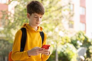 Portrait of teen boy using smartphone. Blogging, surfing, video call. Generation z, mobile generation. Low angle view, copy space. photo