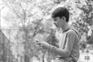 adolescente sentado al aire libre con teléfono inteligente foto