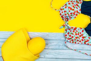 Top view of a swimsuit and a melon in a bag, lying on a blue wooden and yellow background.Summer vacation concept photo