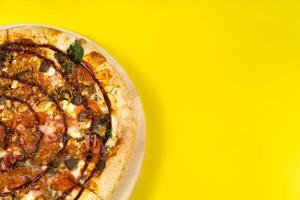 Delicious large pizza with bacon and spinach on a yellow background photo