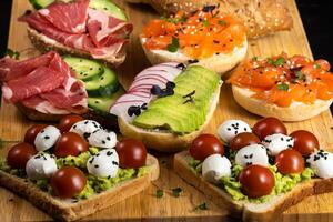 Assorted sandwiches with fish, cheese, meat and vegetables lying on the board photo