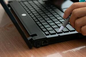 Man working at home holding pen contemplating planning working with laptop computer photo