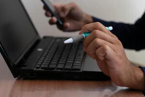 Man working at home, holding a pen, working with a notebook computer photo