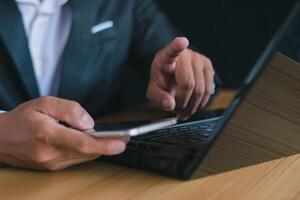 Close-up of a businessman working with a notebook computer and pointing his hand in an office desk thinking about work and goals. photo