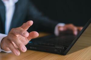 Close-up of a businessman working with a notebook computer and pointing out his hand. photo