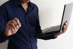 Man working on laptop computer, discussing work online, holding pen, pointing at work, contemplating plans at work photo