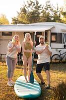 the family is resting next to their mobile home. My daughter is standing with a paddle on a sup board, and her parents pour water on her photo