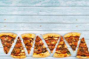 Lots of delicious triangular pizza slices on a blue wooden background photo