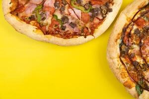 Two different Delicious big pizzas on a yellow background photo