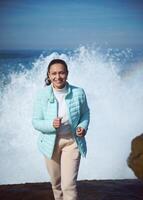 Running woman against huge wave on the Atlantic ocean photo