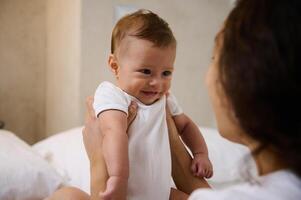 Happy excited baby laughing at mom face, showing positive emotions. Child and baby care concept. photo