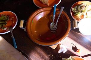 View from above of an empty dirty tagine and plates with the leftover of food after lunch or dinner photo