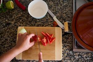 Close-up view from above of a cook chef, using kitchen knife slicing chopping cutting tomatoes on a wooden board photo