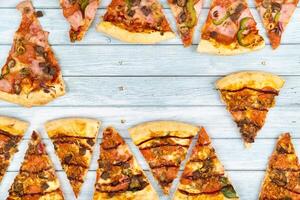 un montón de delicioso triangular Pizza rebanadas en un azul de madera antecedentes foto