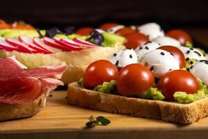 Assorted sandwiches with fish, cheese, meat and vegetables lying on the board photo