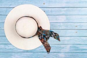 Top view of a straw white hat lying on a blue wooden background.The concept of summer holidays photo
