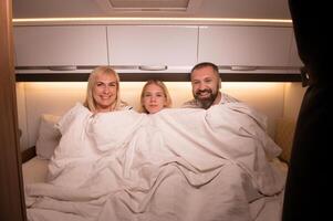 The family is getting ready for bed sitting on the bed in their motorhome photo