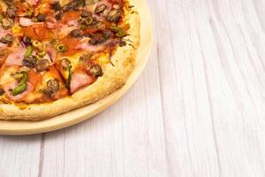 Delicious large pizza with veal and mushrooms on a light wooden background photo