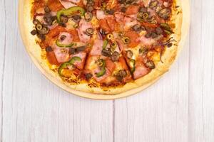 Delicious large pizza with veal and mushrooms on a light wooden background photo