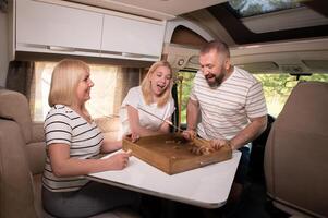 A family of three is playing a board game while sitting in a motorhome photo