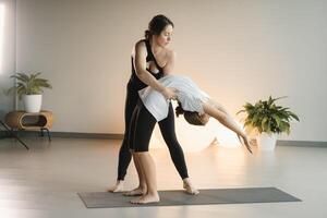 Mom and teenage daughter do gymnastics together in the fitness room. A woman and a girl train in the gym photo