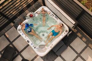 Top view of a family relaxing in an outdoor hot tub in summer photo