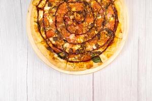delicioso grande Pizza con tocino y Espinacas en un ligero de madera antecedentes foto