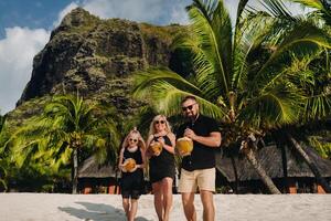 a stylish family in black clothes with coconuts in their hands on the beach of the island of Mauritius.Beautiful family on the island of Mauritius in the Indian ocean photo