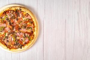 Delicious large pizza with veal and mushrooms on a light wooden background photo