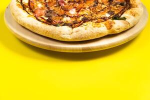Delicious large pizza with bacon and spinach on a yellow background photo