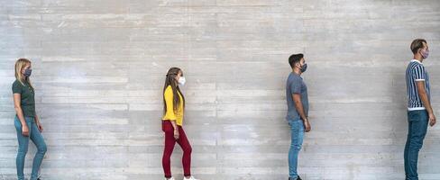 Young people from different cultures and race waiting in queue outside shop market while keeping social distance - Corona virus spread prevention concept photo